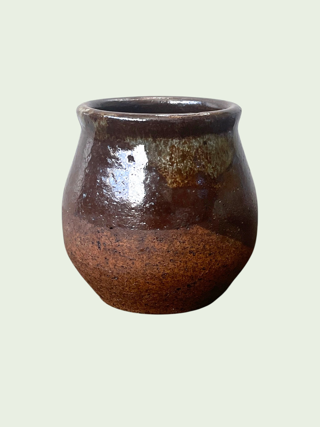Mate caldera artesanal en gres con vidriado marrón oscuro y detalles verdes en el borde, fondo verde menta. Matera Rob®
